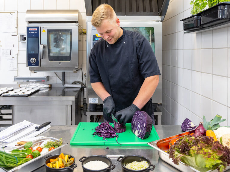 Koch schneidet frisches Gemüse in der Küche des Family Club Harz