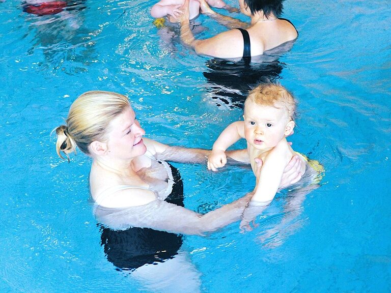 Mutter hält ihr Baby beim Babyschwimmen im Wasser