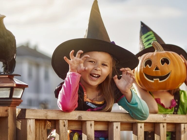 Mädchen als Hexe verkleidet an Halloween mit geschnitztem Kürbis