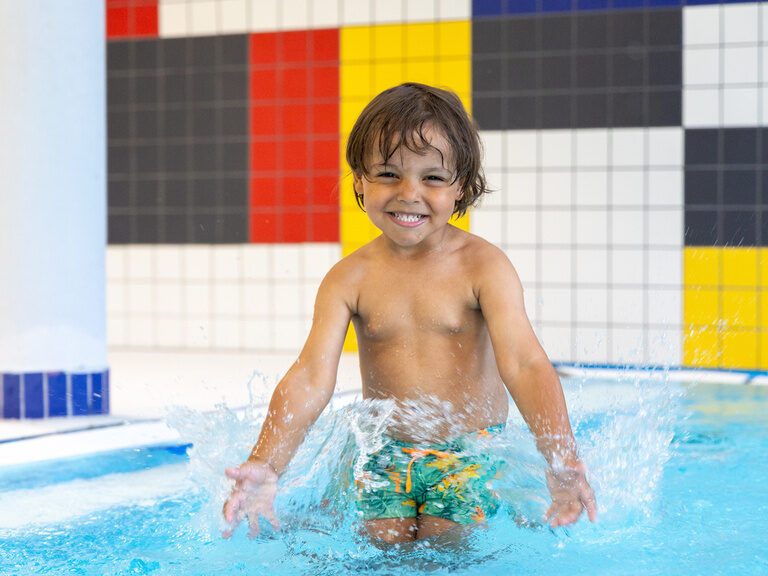 Lachendes Kind plantscht im Pool im Family Club Harz