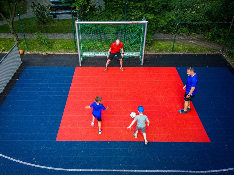 Kinder spielen Fußball auf einem roten Spielfeld im Family Club Harz