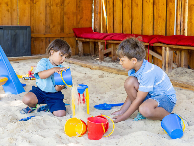 Kinder spielen im Sandkasten mit Eimer und Schaufel