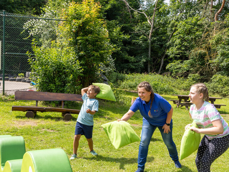 Kinder spielen mit Kissen auf einer Wiese