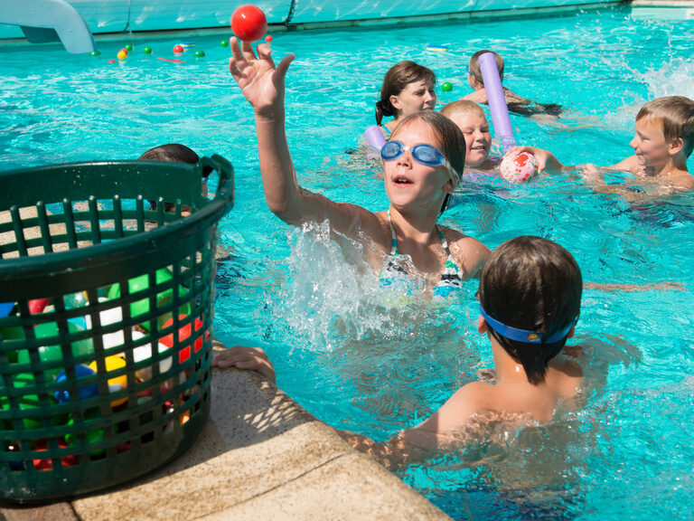 Kinder spielen Wasserspiele im Pool