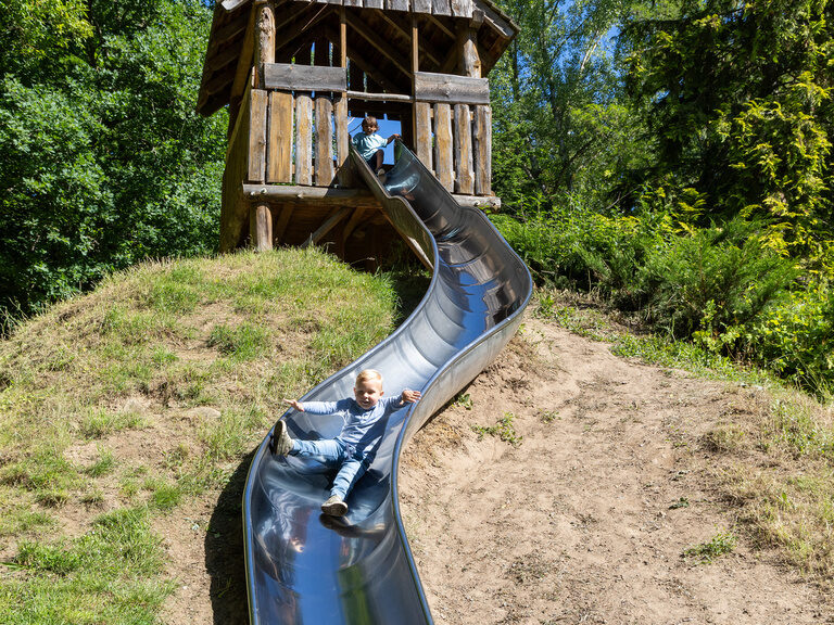 Kinder rutschen auf einer langen Rutsche auf dem Spielplatz im Family Club Harz