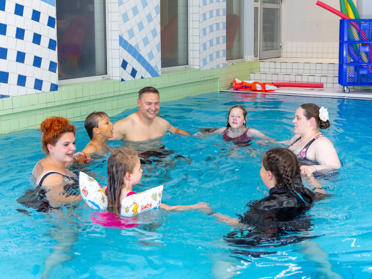 Eltern und Kinder nehmen am Schwimmkurs im Pool teil